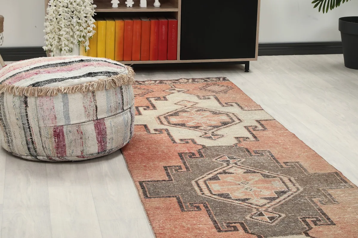 Close-up angled view of the runner rug's pattern and colors, with a decorative ottoman nearby