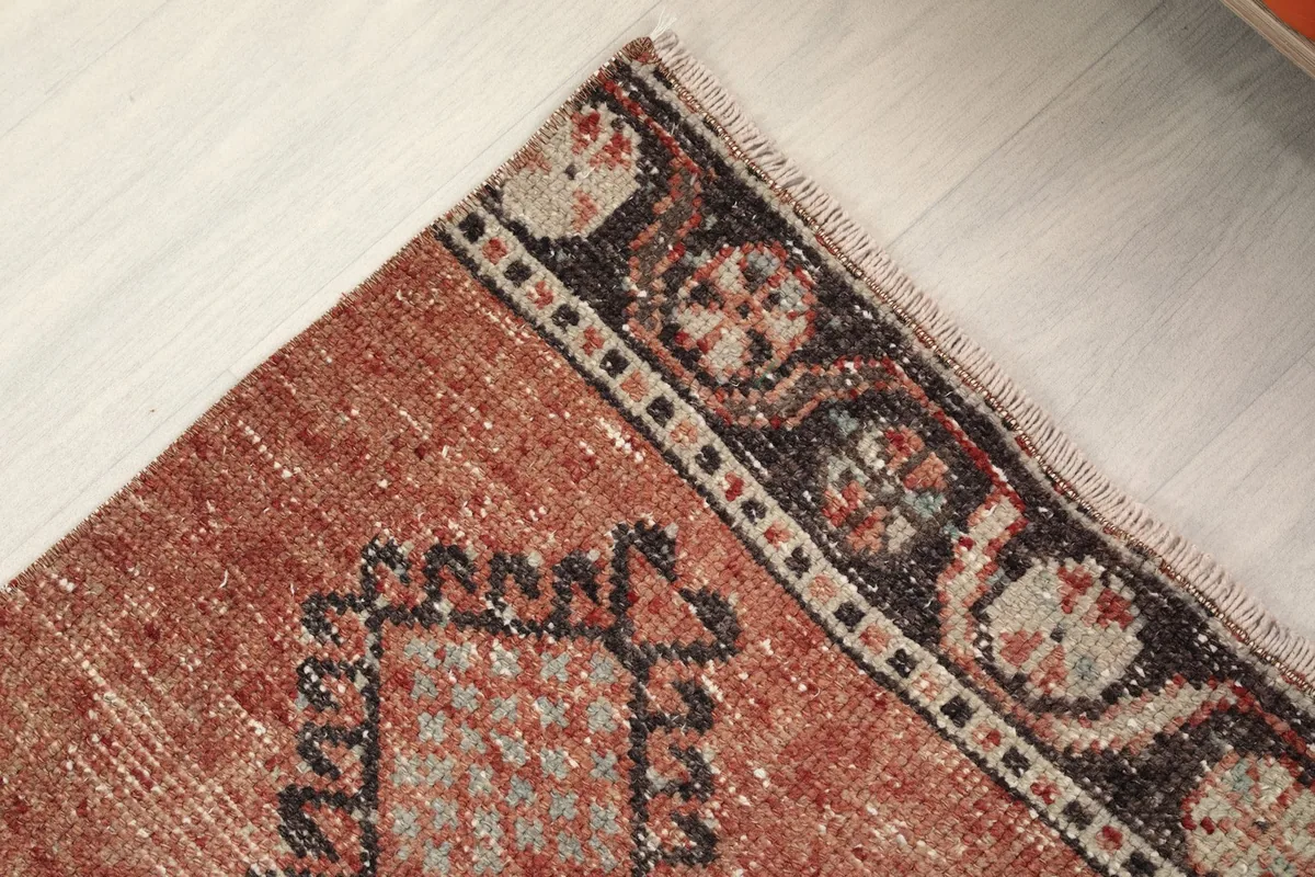 Detail of the runner rug's charcoal border with subtle patterns and the rust field