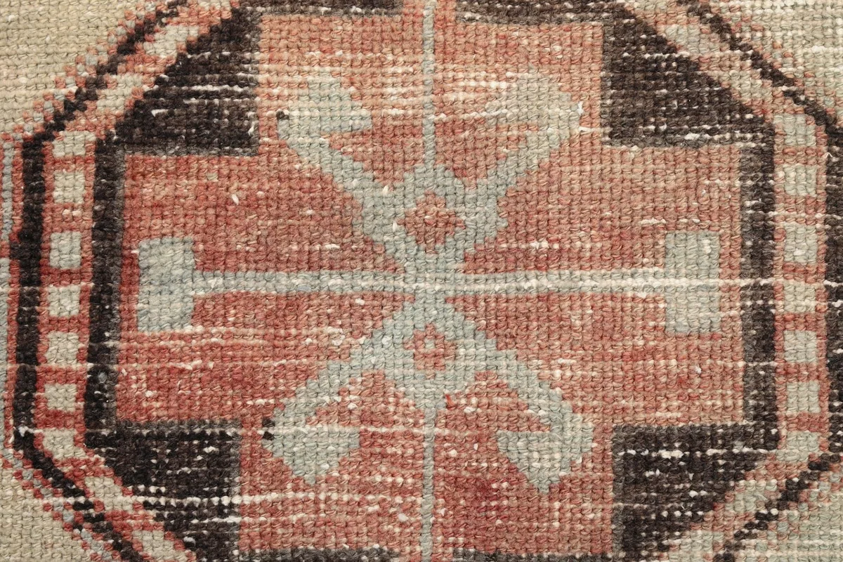 Macro shot of the hand-knotted wool pile, showing texture and color variations in the central motif
