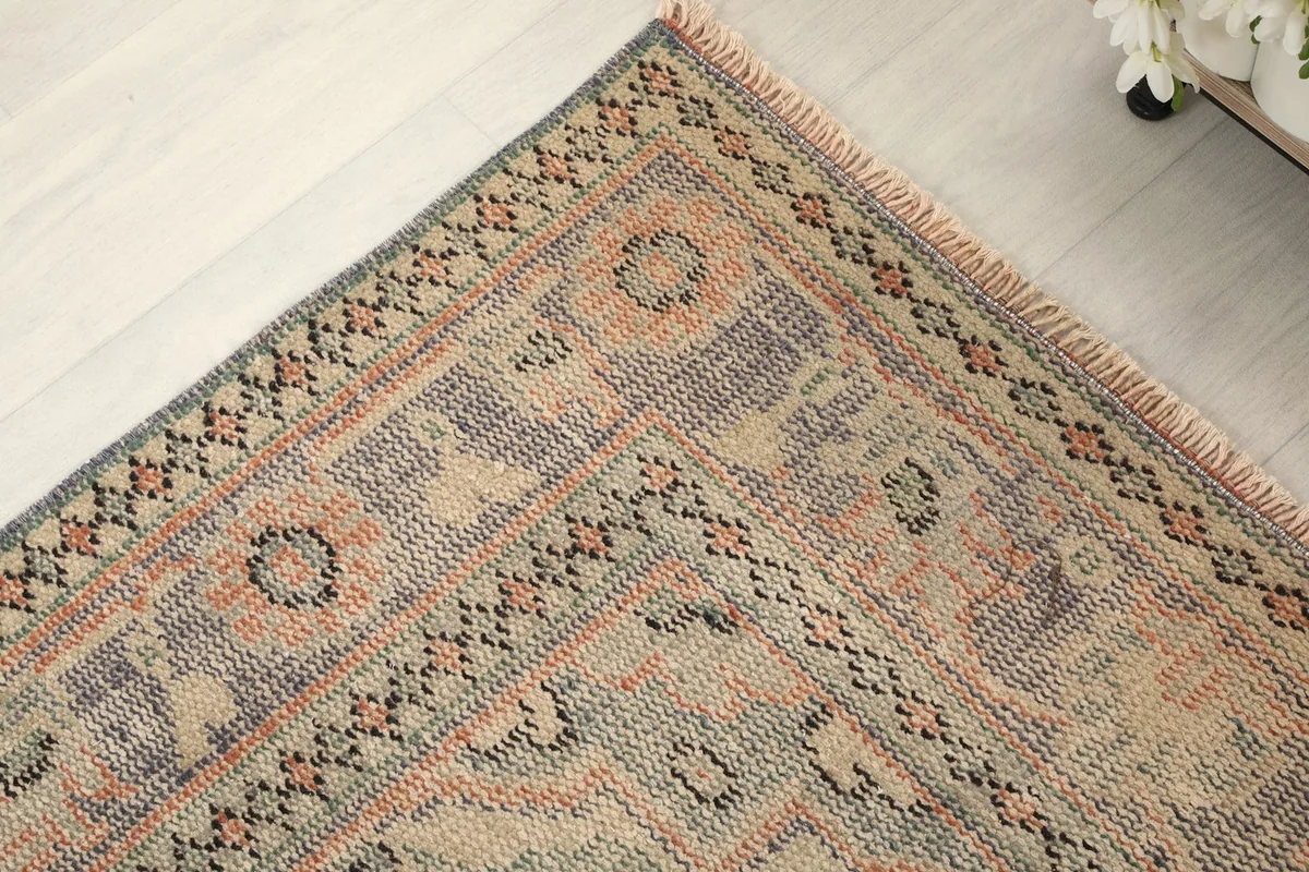 Corner detail of the rug, highlighting the border patterns and aged texture