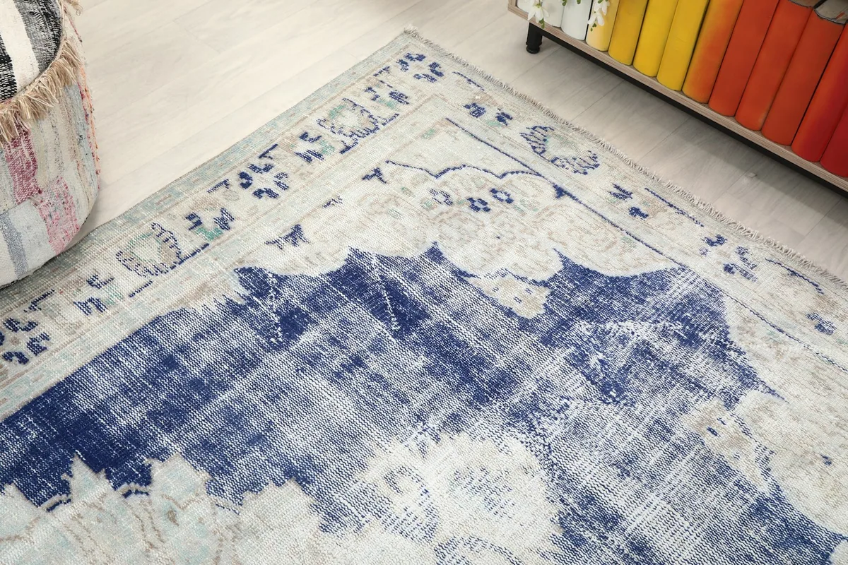 Corner view of the rug, showing the border pattern and distressed blue field
