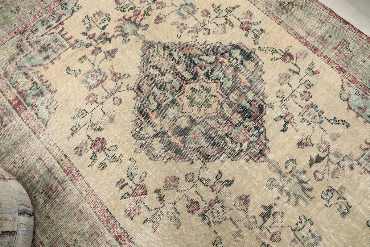 Overhead detail shot of the central navy medallion and beige field with floral motifs.