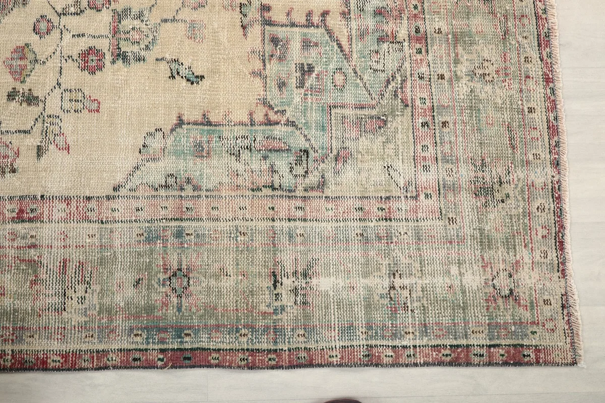 Detail of the green and rose border design and the faded patina on the rug's edge.