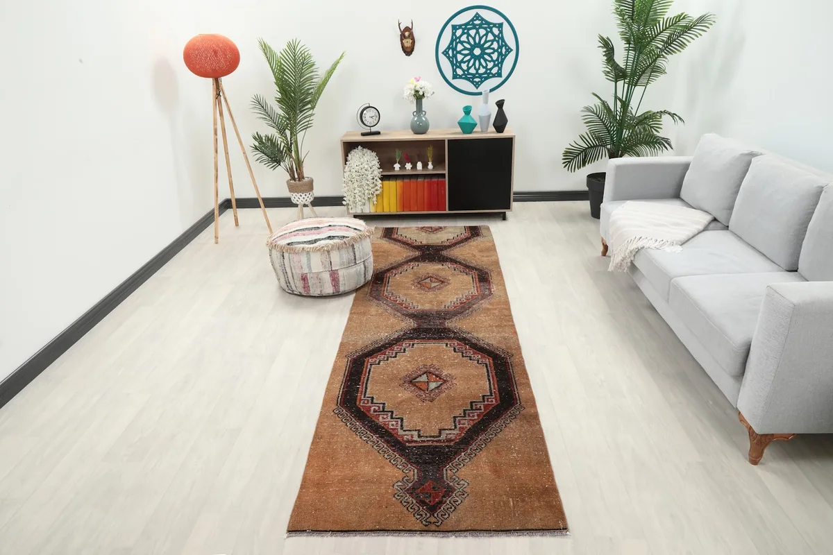 Tan geometric runner rug in a modern living space with a light gray sofa and plants.