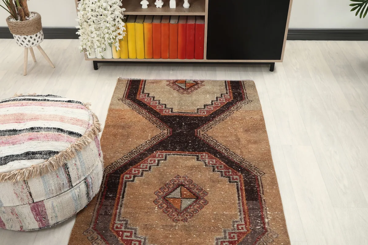 Overhead view of a section of the tan runner rug in a room, next to a decorative pouf.
