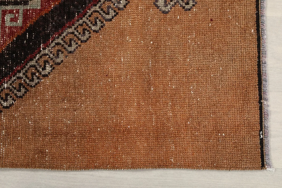 Detailed view of the tan field and edge of the hand-knotted rug, showing its wool texture.