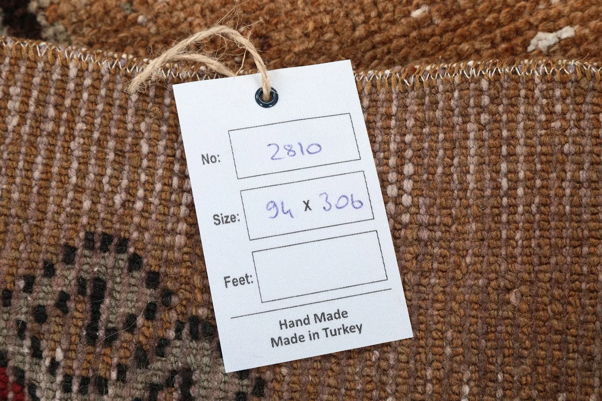 Close-up of the rug's label, indicating its size of 94 x 306 cm and handmade origin from Turkey.