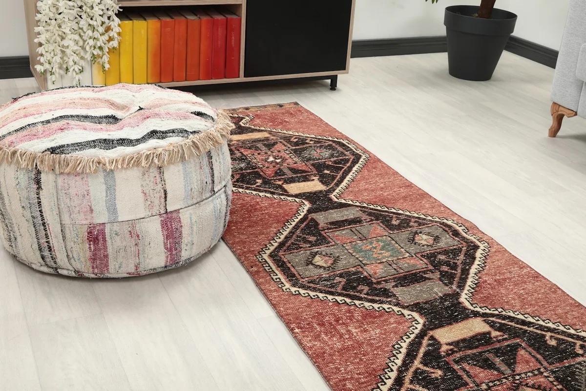 Close-up view of the runner rug on the floor next to a patterned ottoman