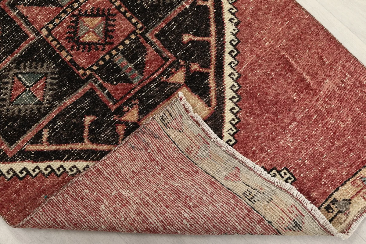 Corner of the rug folded back to reveal the cotton foundation and reverse side