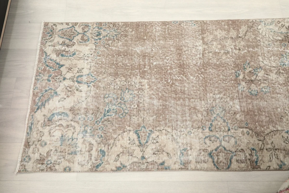Angled view of the rug's surface, showing the subtle color variations and distressed areas