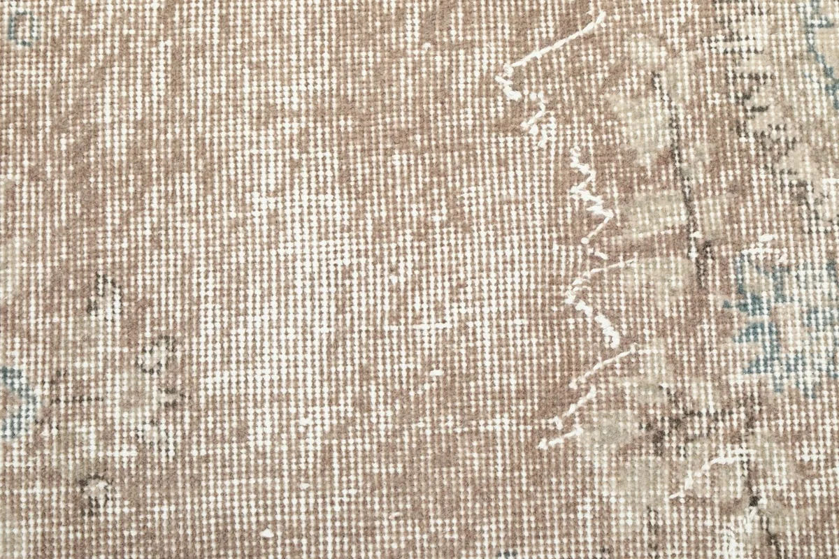 Texture shot of the low wool pile and visible cotton foundation through the faded design