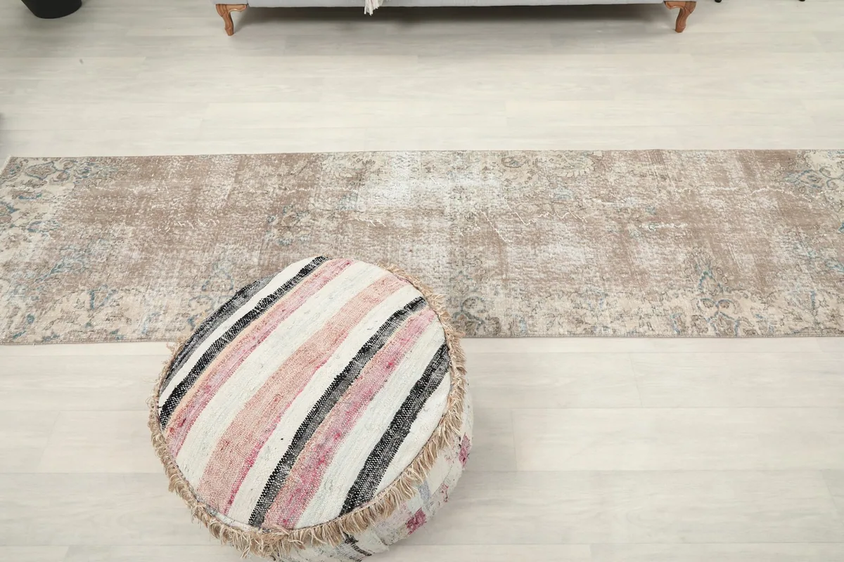Top-down view of the entire runner rug, with a decorative ottoman in the foreground