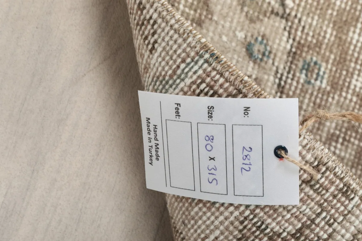 Close-up of the rug's tag, indicating hand-made in Turkey and size 80 x 315 cm