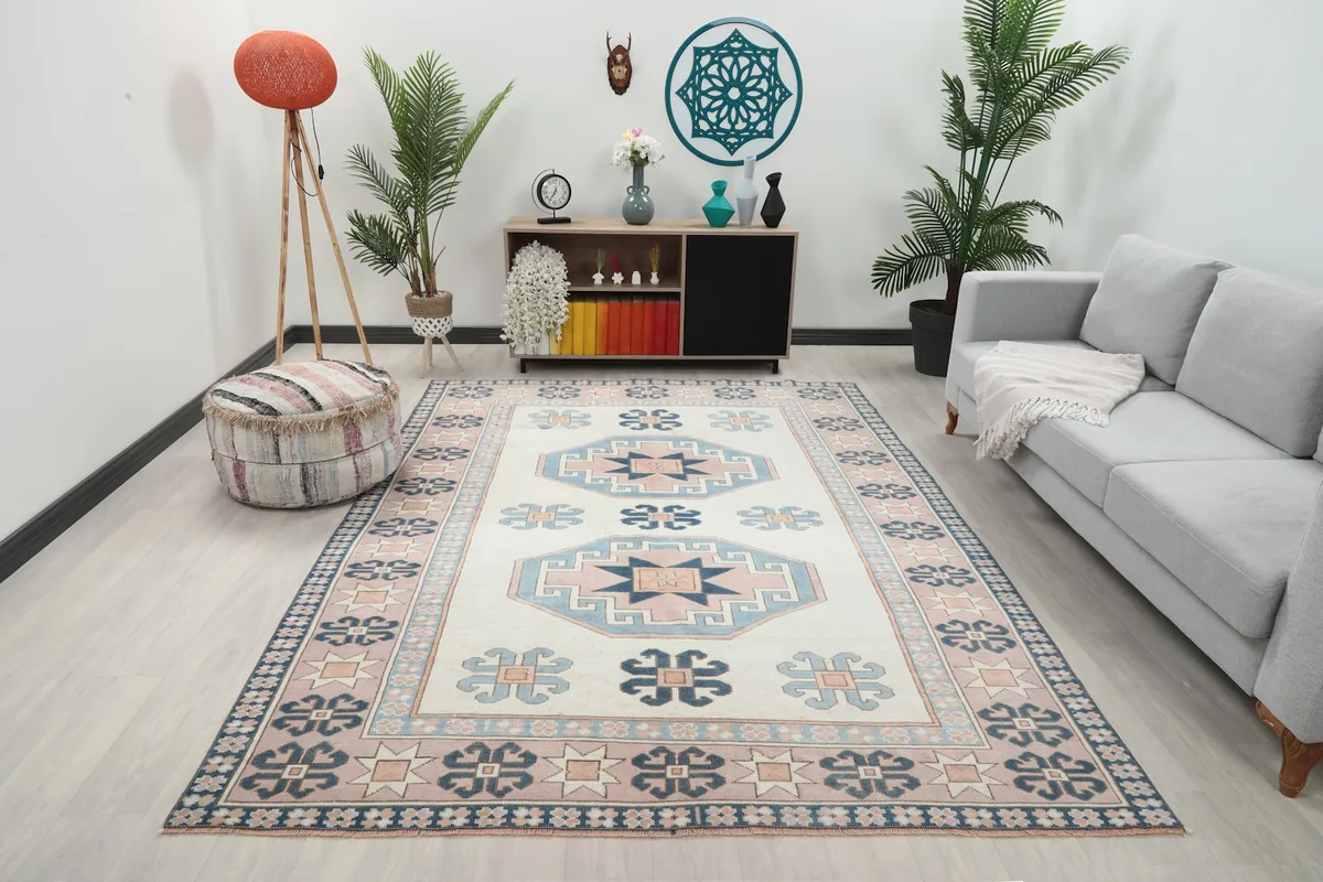 Vintage Anatolian rug displayed in a modern living room setting with a sofa and plants.