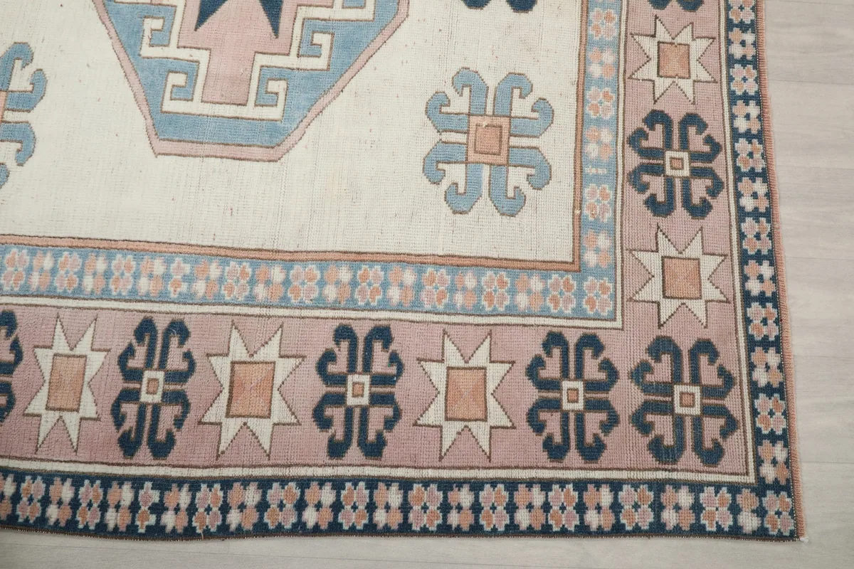 Detail of the rug's border, featuring navy, pink, and tan geometric patterns and stars.