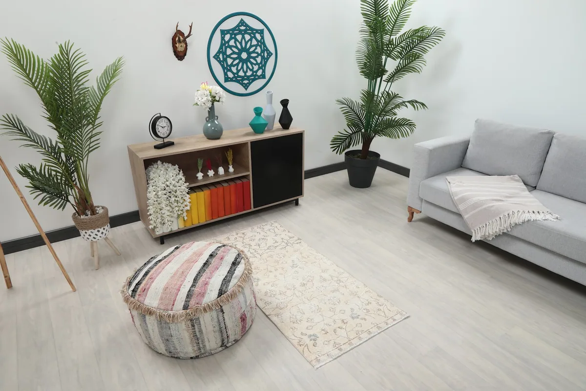 Overhead view of the cream floral rug in a living space with a couch and ottoman