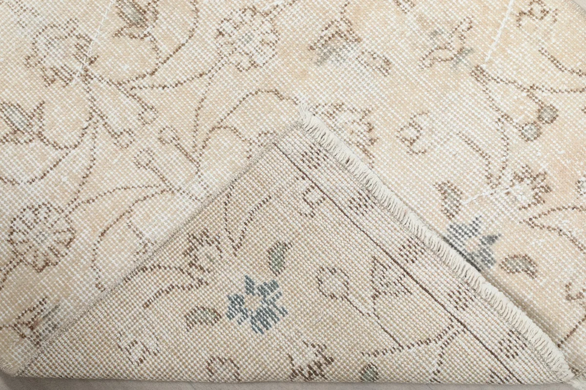 Corner of the rug folded to show the cotton foundation and reverse side of the knotting