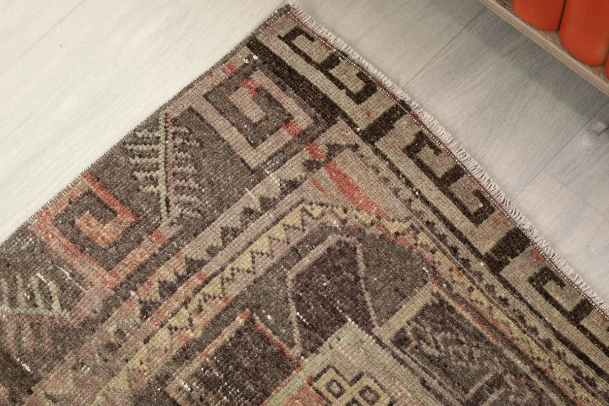 Corner detail of the rug showing the charcoal border with geometric designs and a hint of fringe