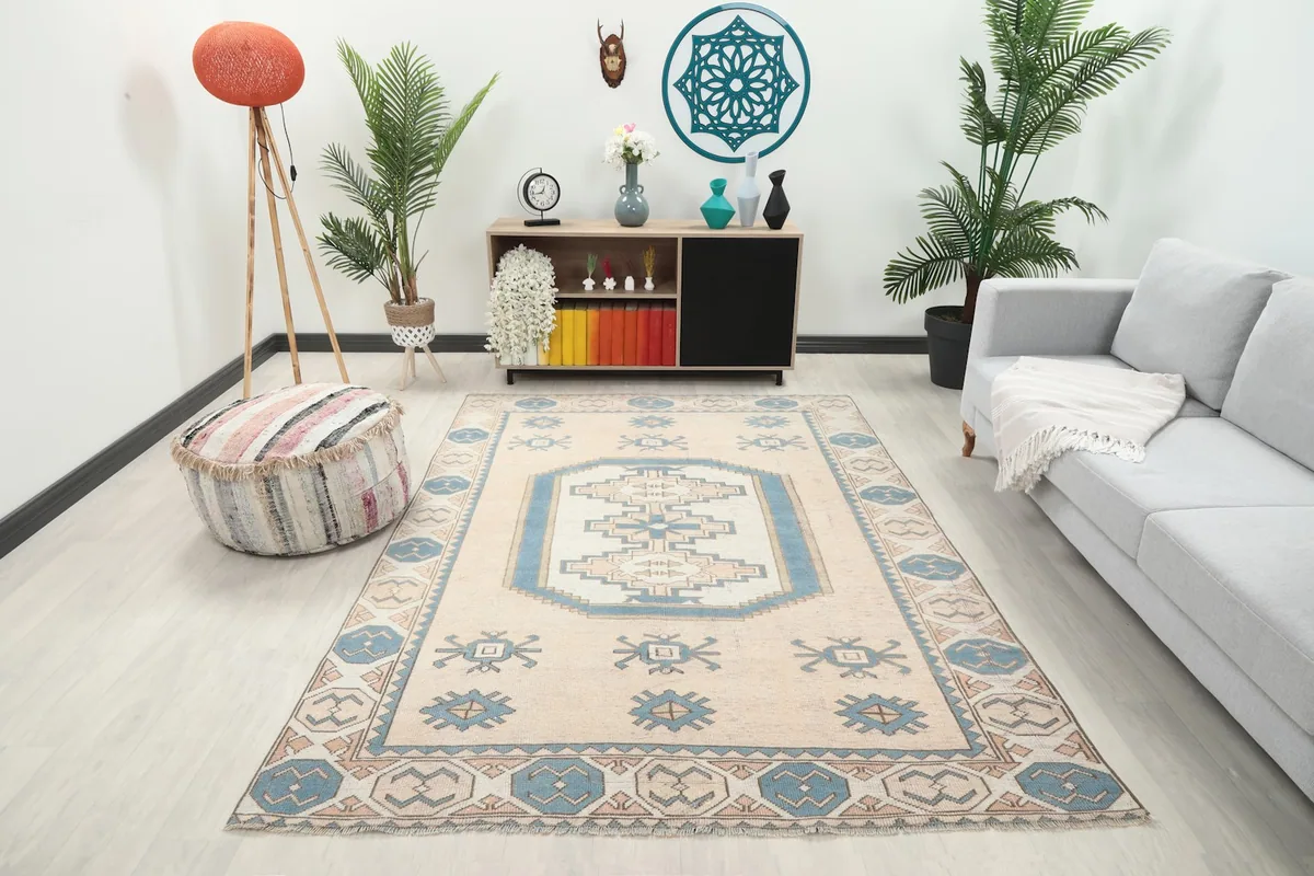 Vintage beige and blue rug placed in a modern living room setting with a light gray sofa