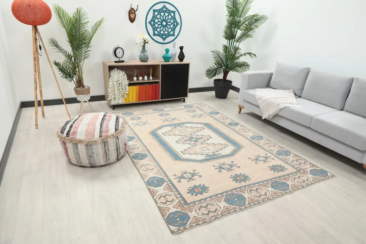 Overhead view of the beige and blue geometric rug in a living room with a side table and plants