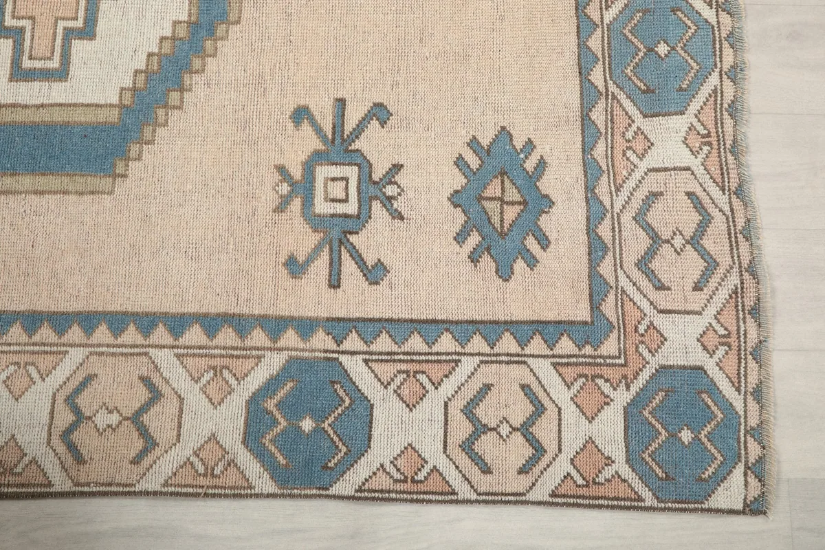 Close-up of the border pattern and small tribal motifs on the beige rug field