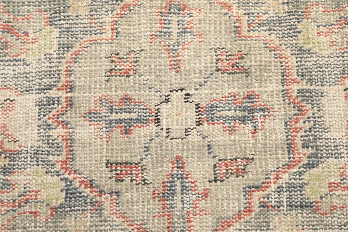 Close-up of the intricate knotting and faded blue and rust colors in the pattern