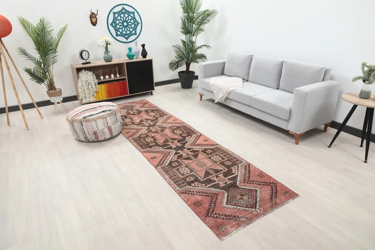 Angle view of the rose and charcoal runner rug in a contemporary room setting with light flooring.