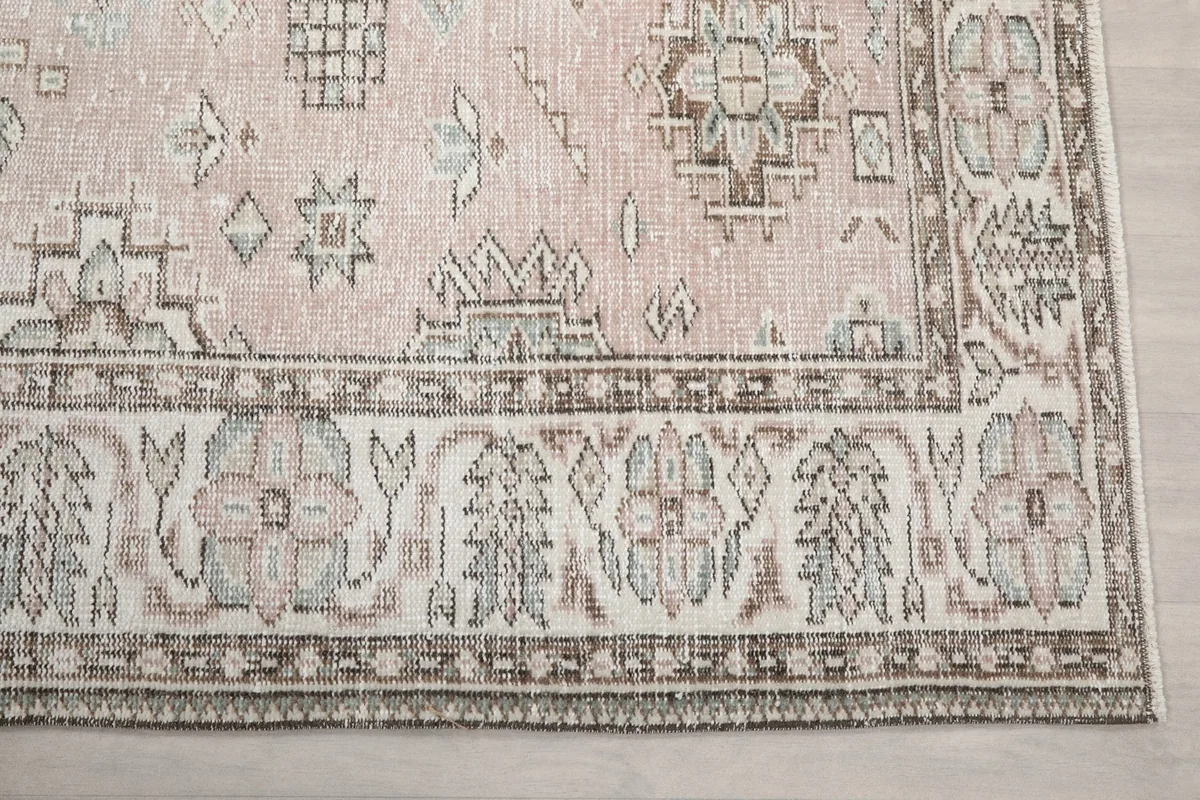 Close-up of the rug's border with floral and geometric motifs in beige and brown