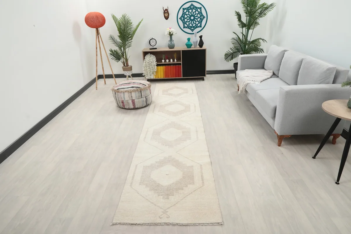 Vintage cream and tan runner rug displayed in a bright modern hallway with light wood flooring and a gray sofa.