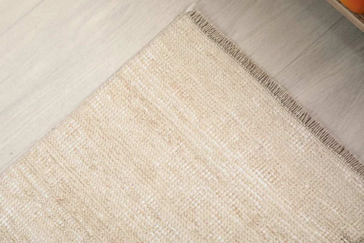 Close-up of the rug's corner, revealing the low wool pile and the tightly woven cotton foundation.