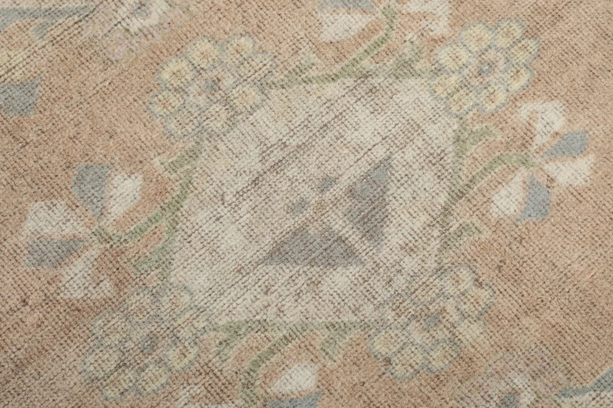 Close view of a faded geometric motif within the rose central field, showing texture