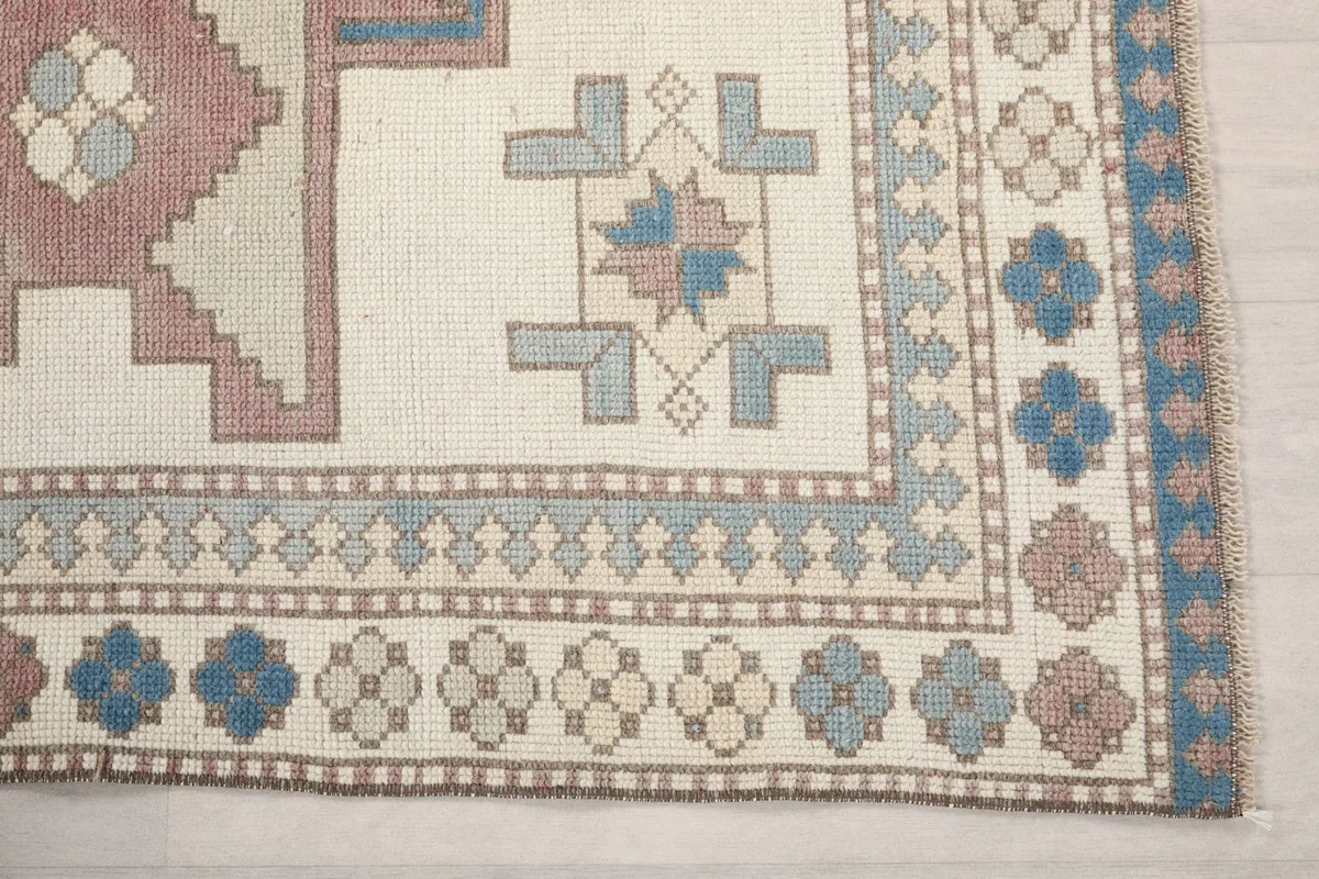 Detailed view of the rug's border and corner motifs in blue and beige