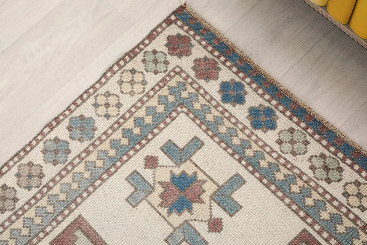 Detailed corner of the rug, highlighting the varied blue and rose border patterns