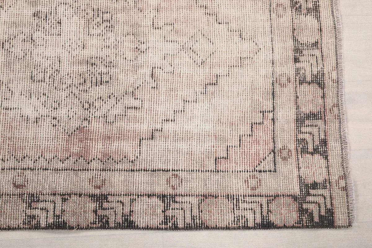 Detail of the rug's border and corner, highlighting geometric motifs and faded colors
