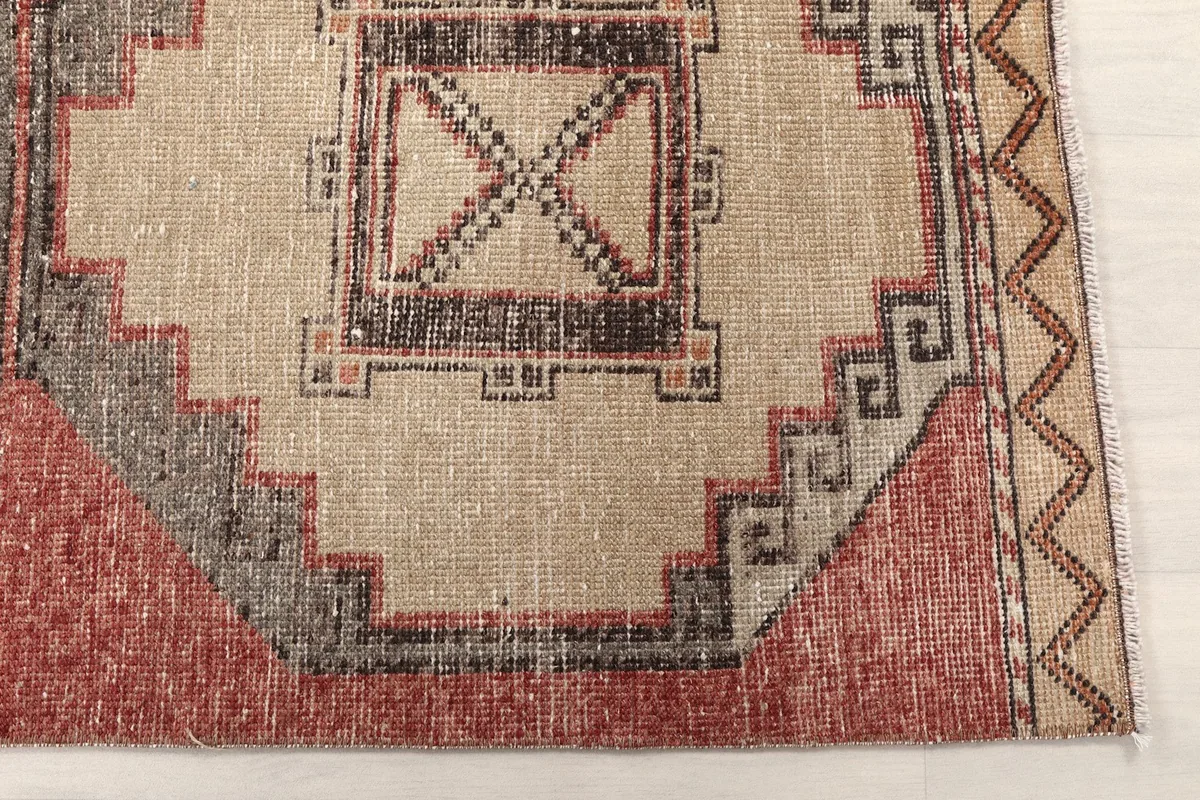 Detailed view of one geometric medallion with rust and beige colors and gray outlines