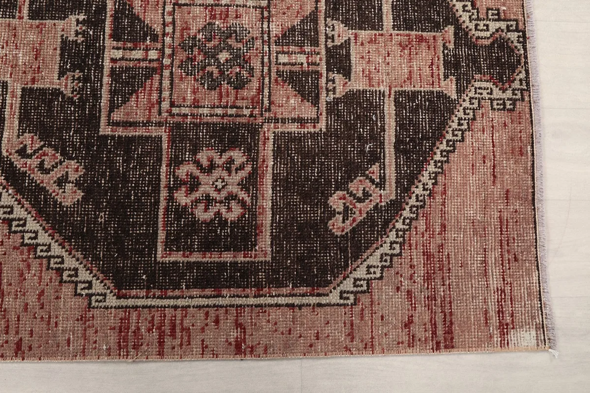 Detailed view of the charcoal geometric motif against the rose field, showing subtle wear.