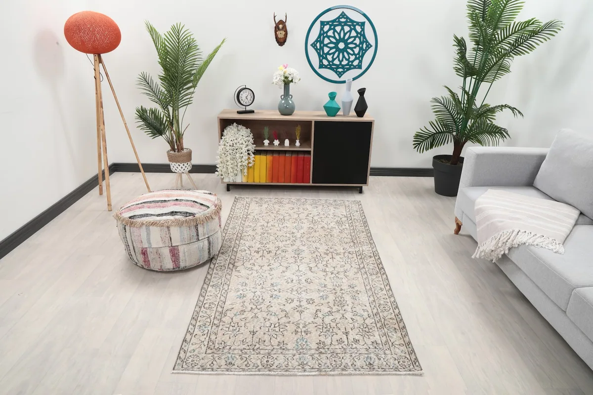 Beige vintage rug displayed in a bright living room setting with a sofa and plants