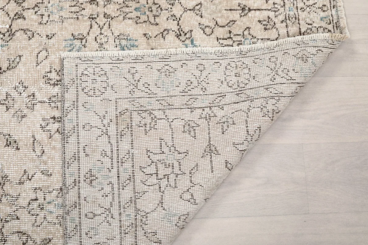 Folded corner of the rug, showing the reverse side and the fringe detail