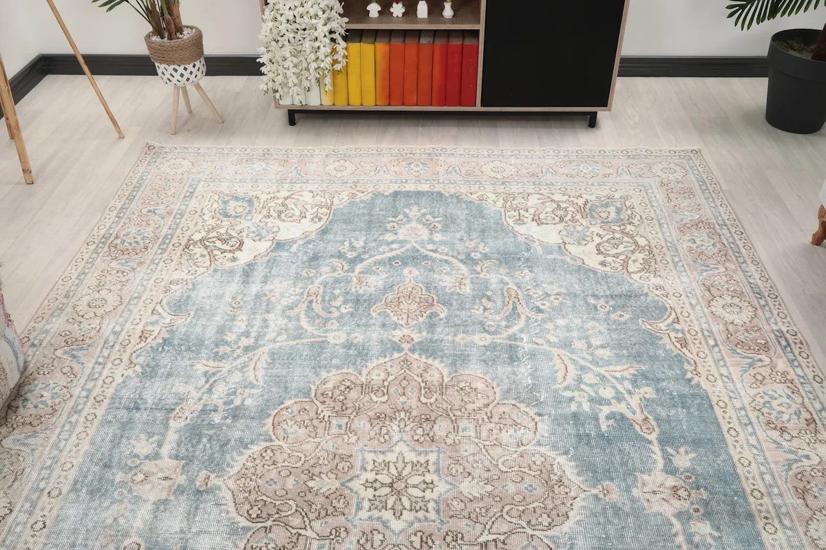 Wide shot of the blue and rose vintage rug in a room, showing its large size