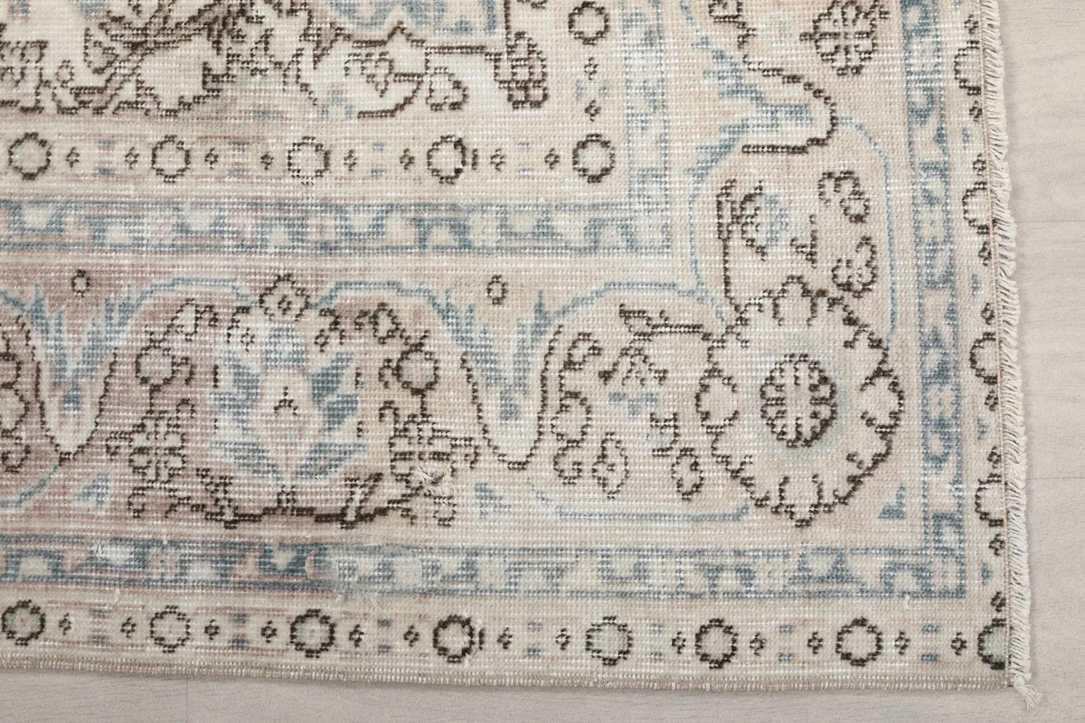 Detailed view of the ivory border and corner motifs of the hand-knotted rug