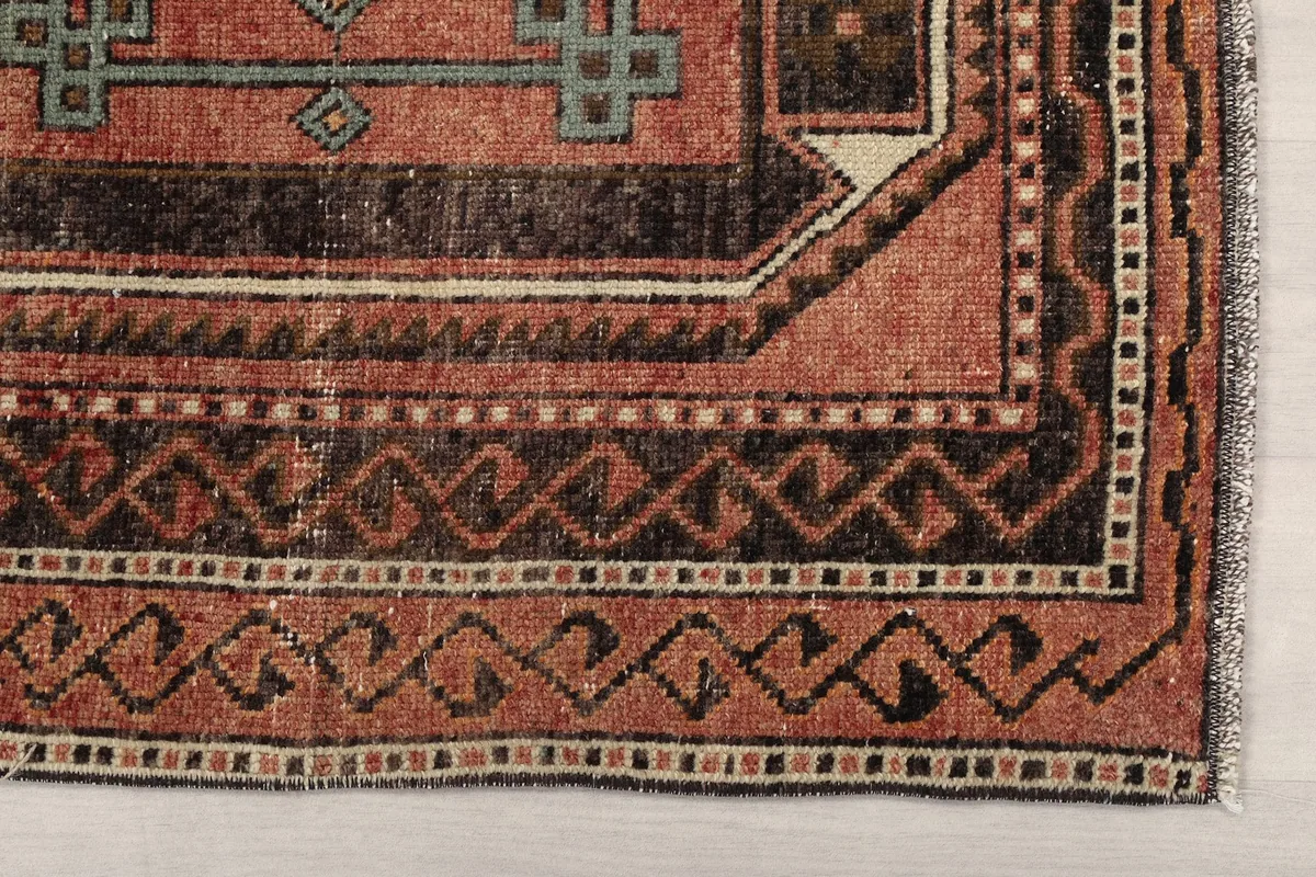 Detail of the rug's border showing tribal patterns and faded colors