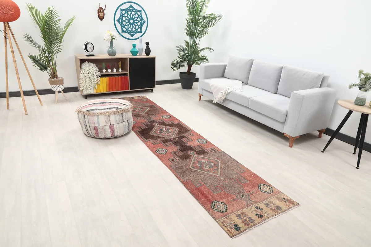 Angled view of the rust runner rug in a room, showing its length and geometric pattern.