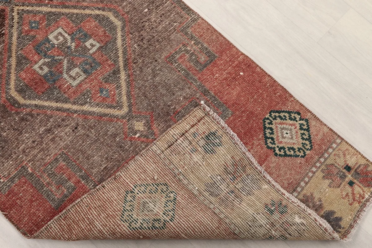 Folded corner of the runner rug revealing the back of the hand-knotted construction and cotton foundation.