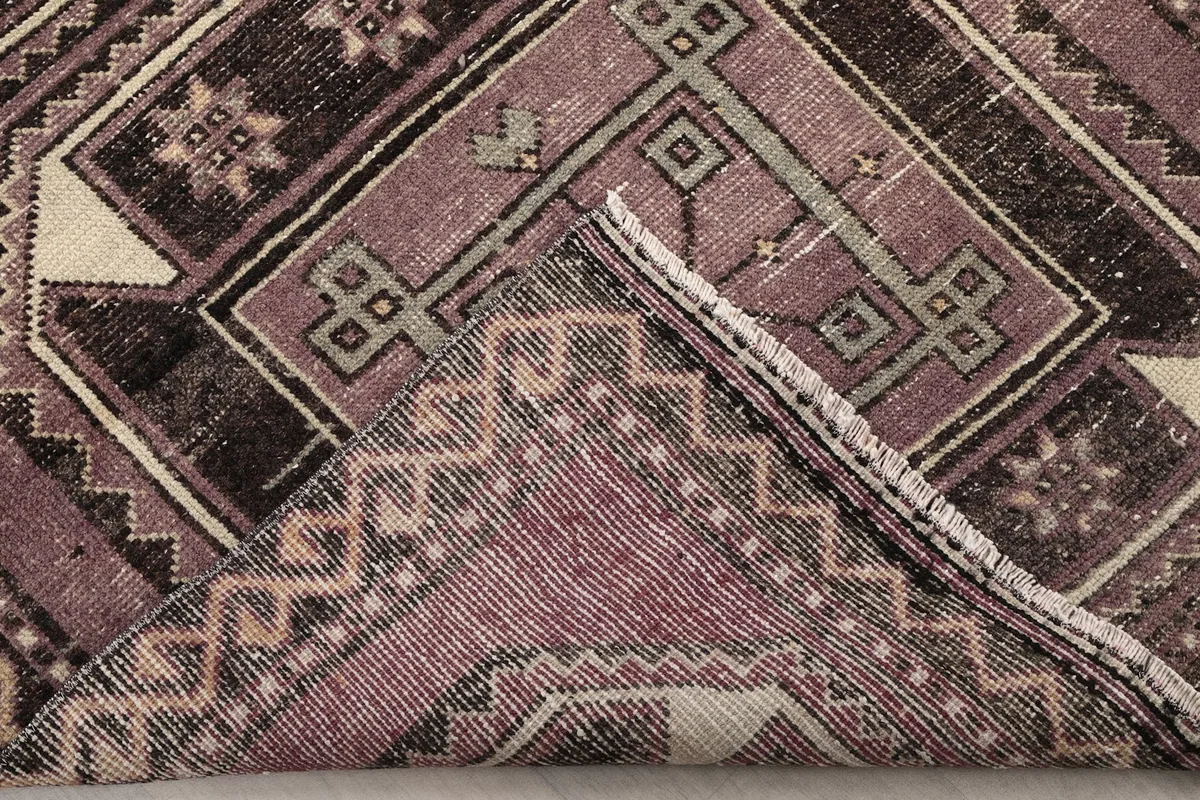 Corner of the runner rug folded to show the hand-knotted back and fringe