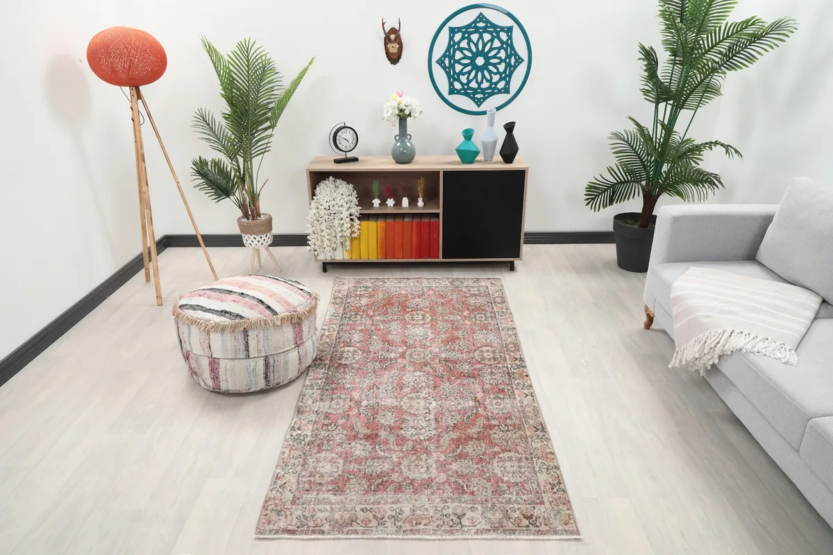 Small rose vintage rug in a living room setting with a light couch and wooden furniture