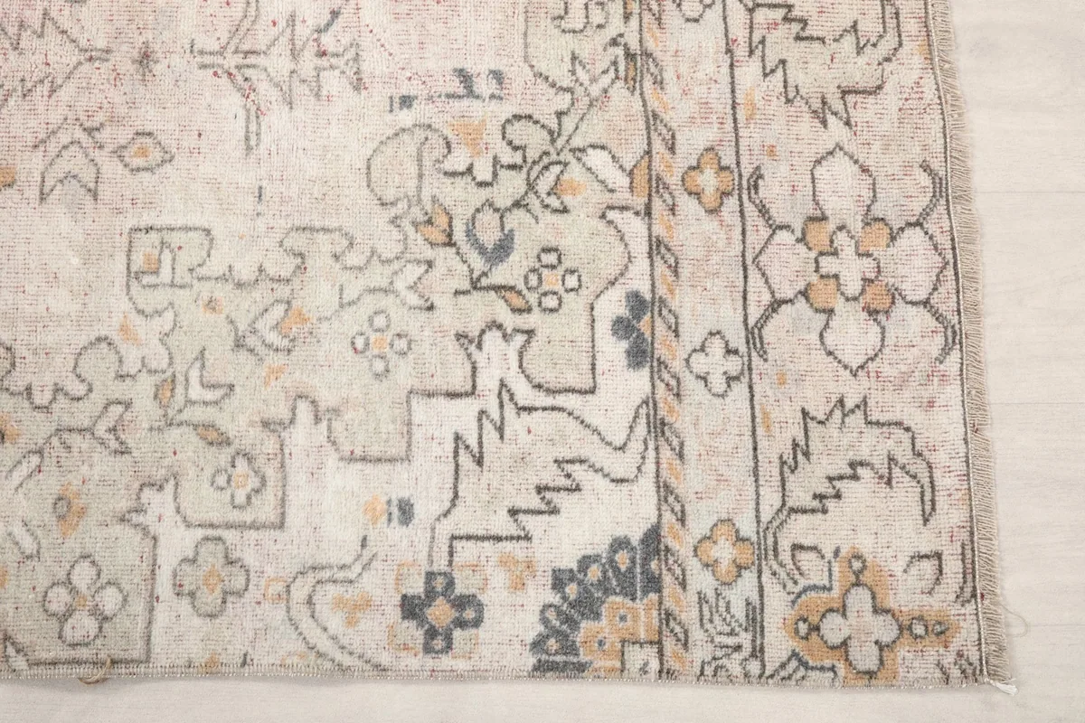 Detailed view of the rug's border and corner, showing geometric motifs in gold and gray
