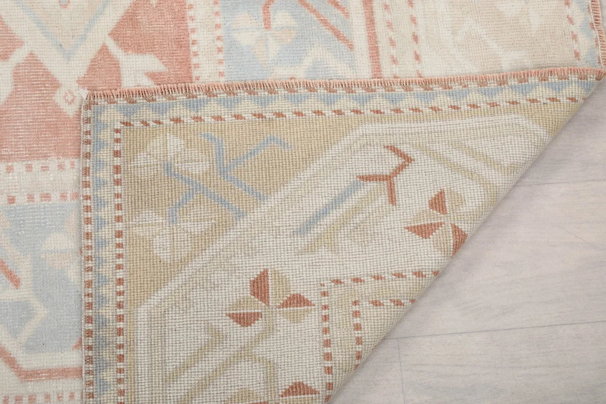 Underside of the rug with a corner lifted, showing the cotton foundation