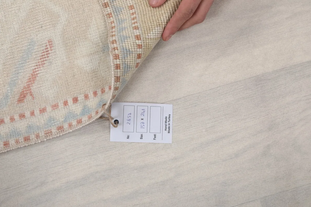 Hand holding up the rug to show the product tag with size and origin information