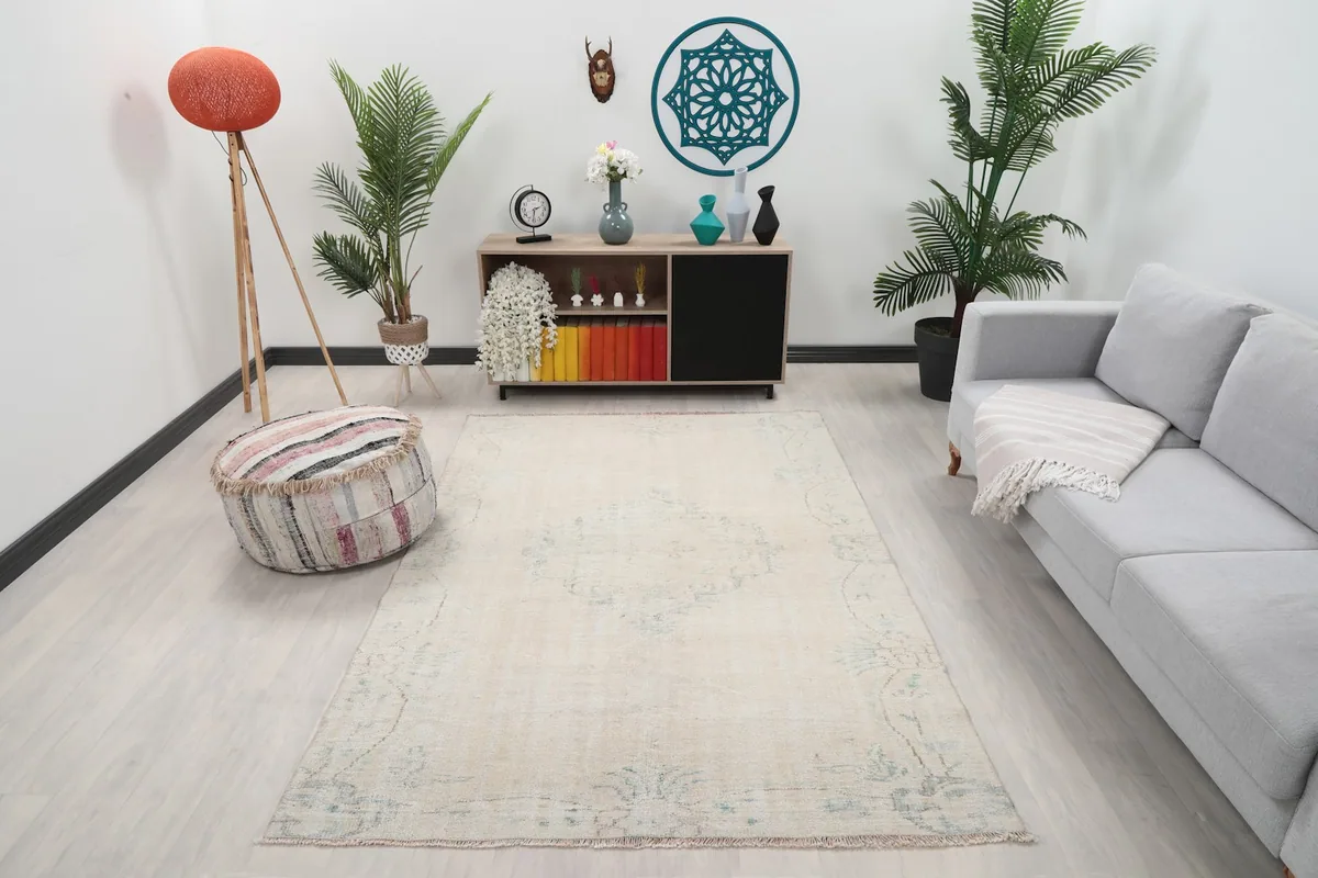 Vintage ivory rug displayed in a living room setting with a light gray sofa and modern decor.