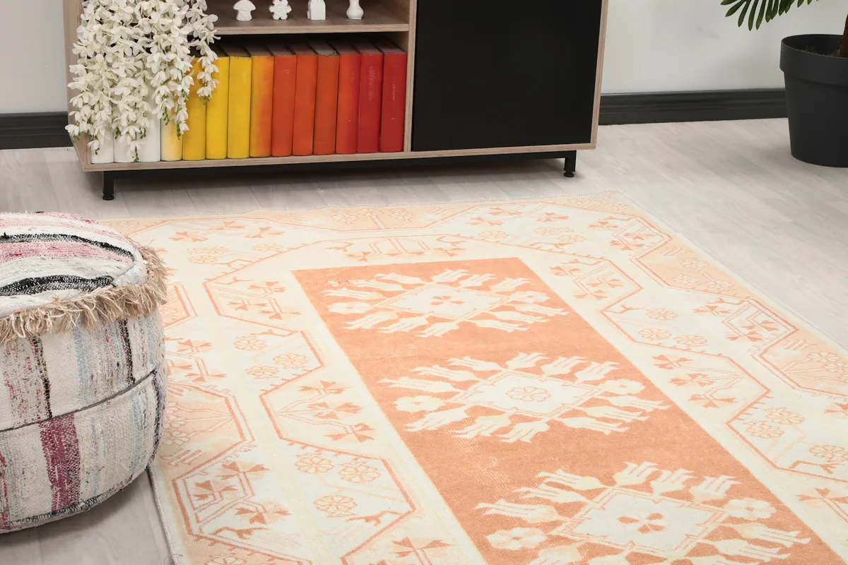 Close-up detail of the rug's orange central field and cream border, showing floral motifs and texture.